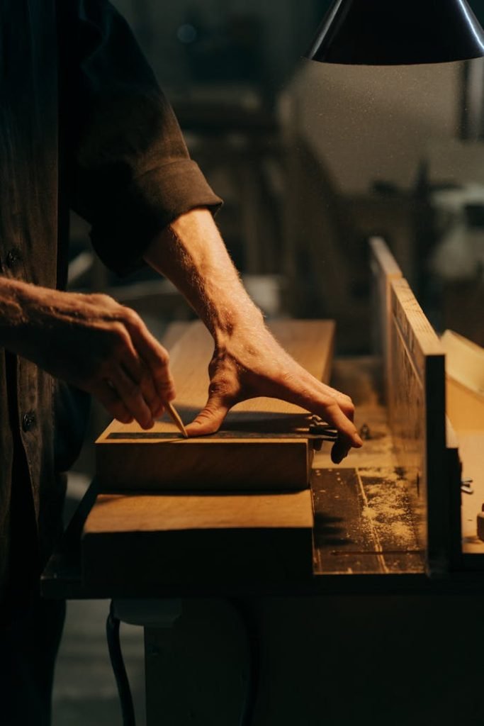 A craftsman skillfully sanding a wooden plank in a well-lit workshop.